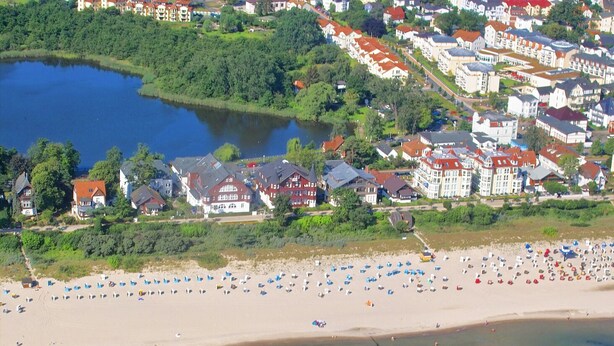 An aerial view of a coastal town with a beach, houses, and a lake. - Villa Vineta Appartement 6/7 (Seebad Bansin)
