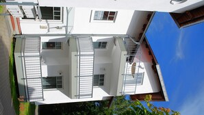 Ein zweistöckiges Gebäude mit flachem Dach, vielen Fenstern und einem sichtbaren Balkon.
