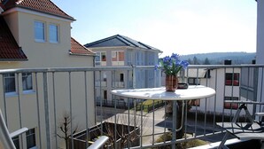 Ein Balkon mit Tisch, Topfpflanze und Blick auf umliegende Gebäude.