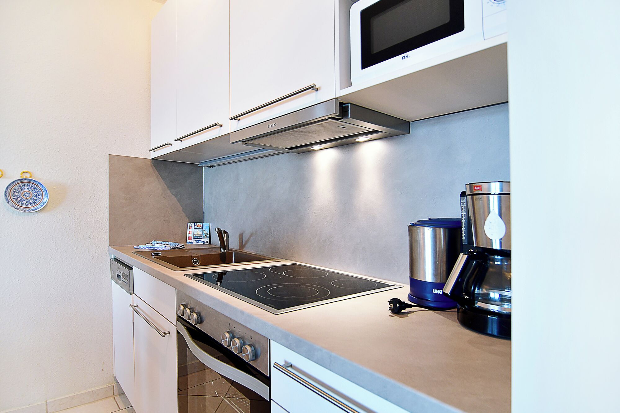 A compact kitchen with a stove, microwave, and coffee maker.