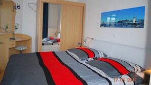 A bedroom with a bed, a desk, a mirror, and a painting on the wall. - Seeschloss Appartement 05 (Seebad Heringsdorf)