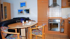 A compact kitchen with a round table, chairs, a stove, and a toaster. - Seeschloss Appartement 05 (Seebad Heringsdorf)