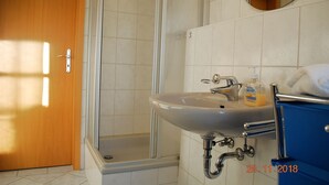 Ein Badezimmer mit Dusche, Waschbecken und Spiegel.