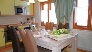 Un comedor con una mesa de madera, sillas y un centro de mesa floral.