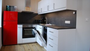 A compact kitchen with white cabinets, a red refrigerator, and a black countertop. - Villa Anna an der Ahlbecker Strandpromenade, App. 05 (Ostseebad Heringsdorf OT Ahlbeck)