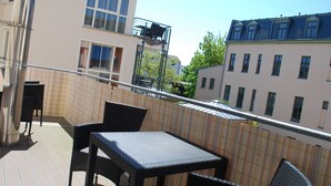 A balcony with a table and chairs, a metal railing, and buildings in the background. - Villa Anna an der Ahlbecker Strandpromenade, App. 05 (Ostseebad Heringsdorf OT Ahlbeck)