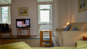 Een woonkamer met een televisie, een bank, een stoel en een kleine houten tafel.