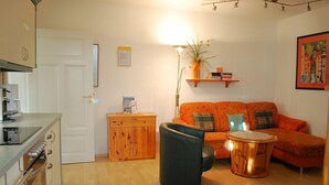 Een woonkamer met een bank, een salontafel, een kast en een deur.