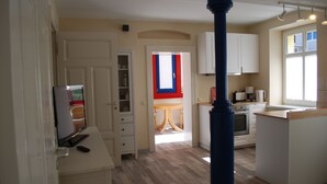 Una cocina moderna con armarios blancos, una isla central y un comedor con cortinas rojas y azules.