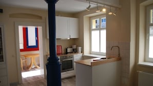 Cocina moderna con armarios blancos, encimera de madera y ventana que proporciona luz natural.