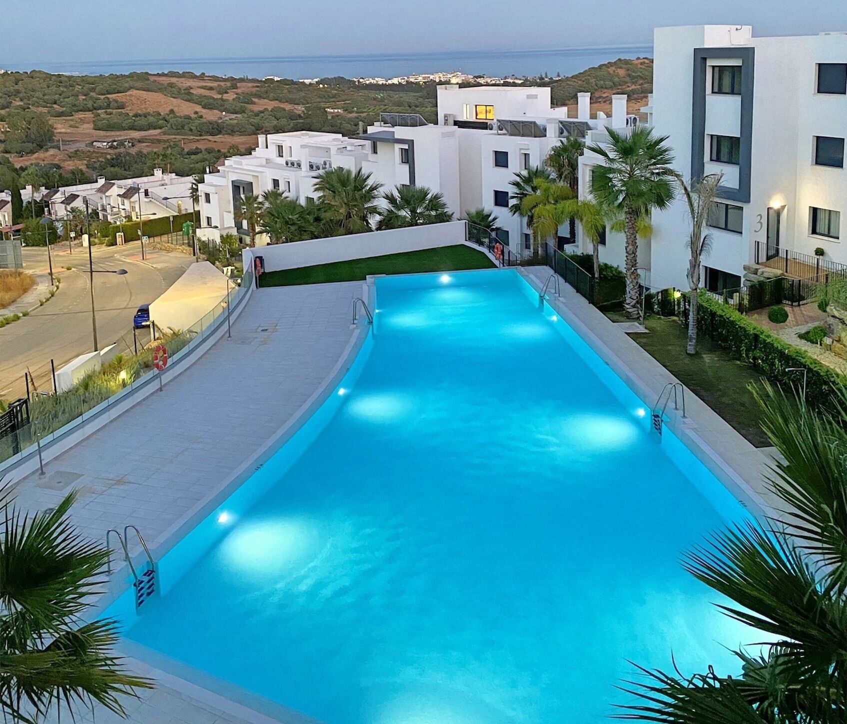 A swimming pool with a view of a coastal landscape, surrounded by modern buildings.