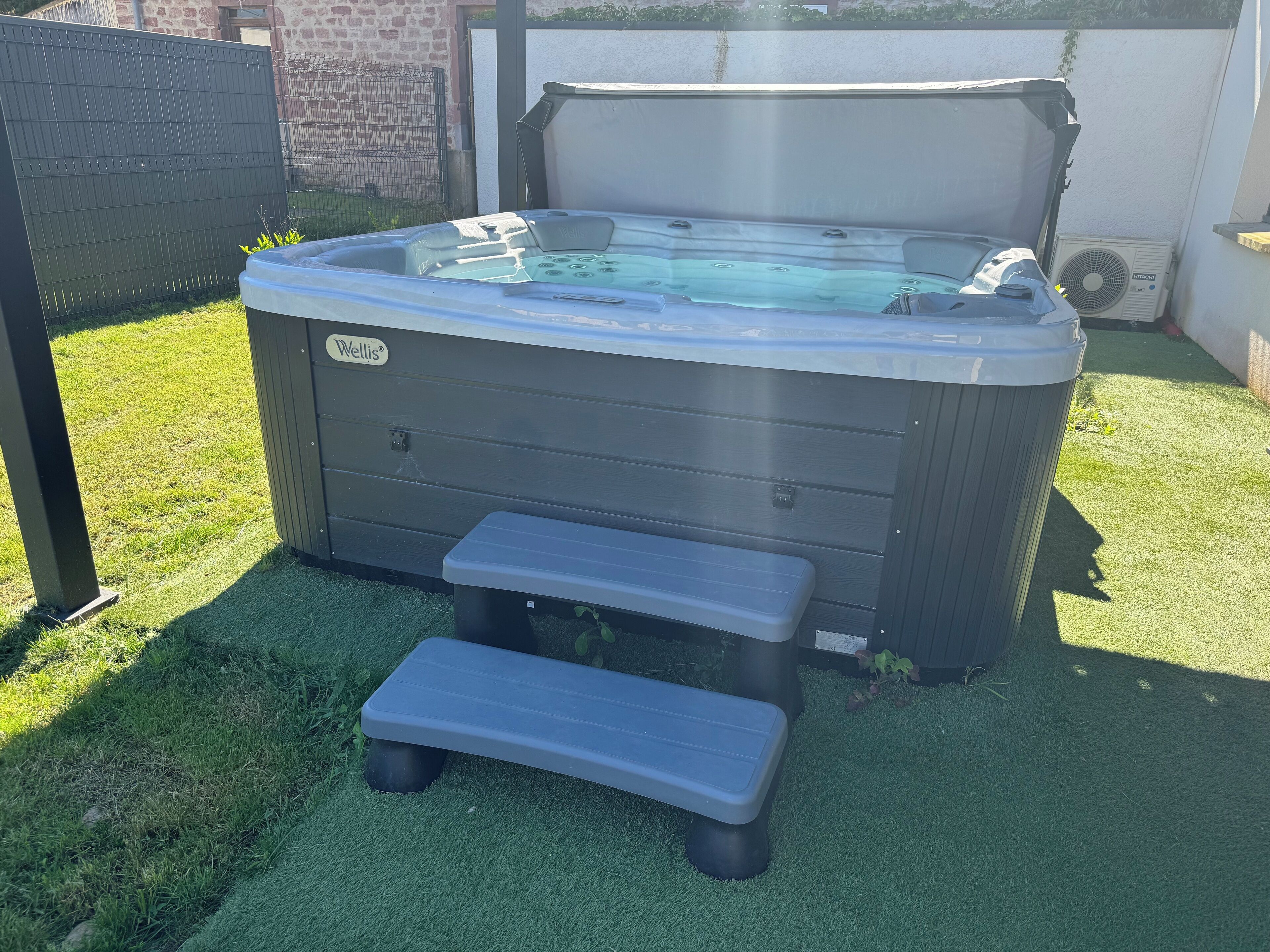 Un bain à remous avec un banc devant, entouré de gazon synthétique.