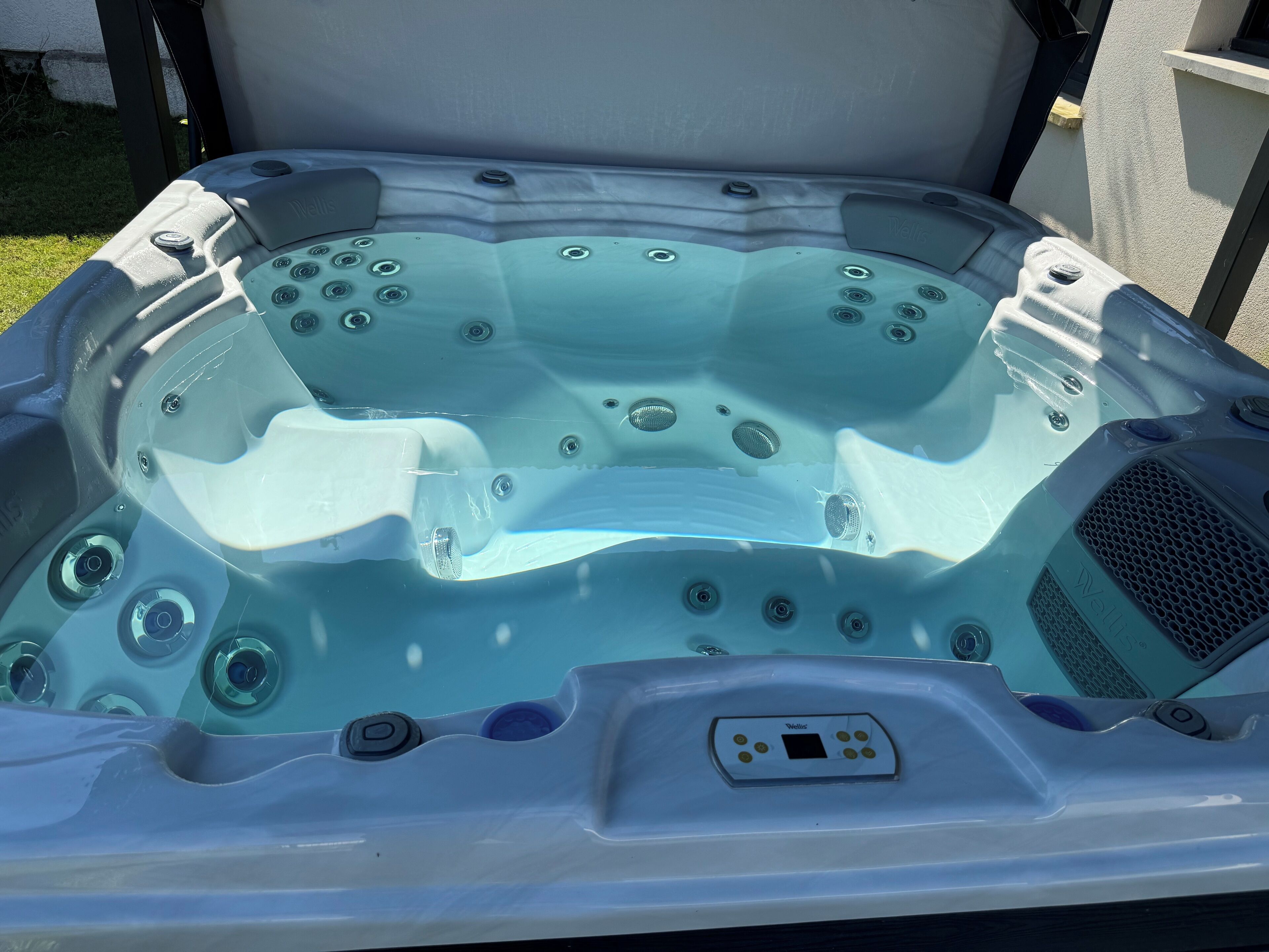 A hot tub with multiple jets, a control panel, and a built-in speaker.