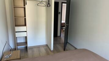Un dormitorio con cama, un armario de madera con varios estantes y una puerta que da a otra habitación.
