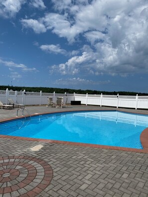 Ein Swimmingpool mit weißem Zaun und Liegestühlen darum.