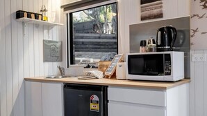 Une cuisine compacte équipée d’un four à micro-ondes, d’une machine à café et d’un petit réfrigérateur.