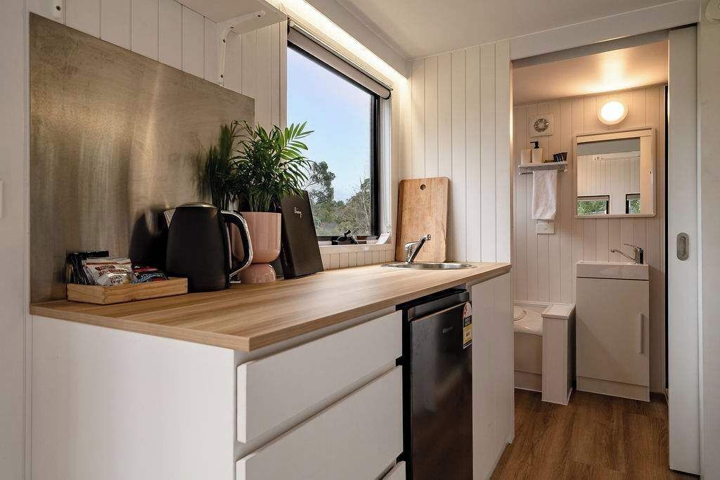 A compact kitchen with a wooden countertop, a sink, a dishwasher, and a window providing natural light.