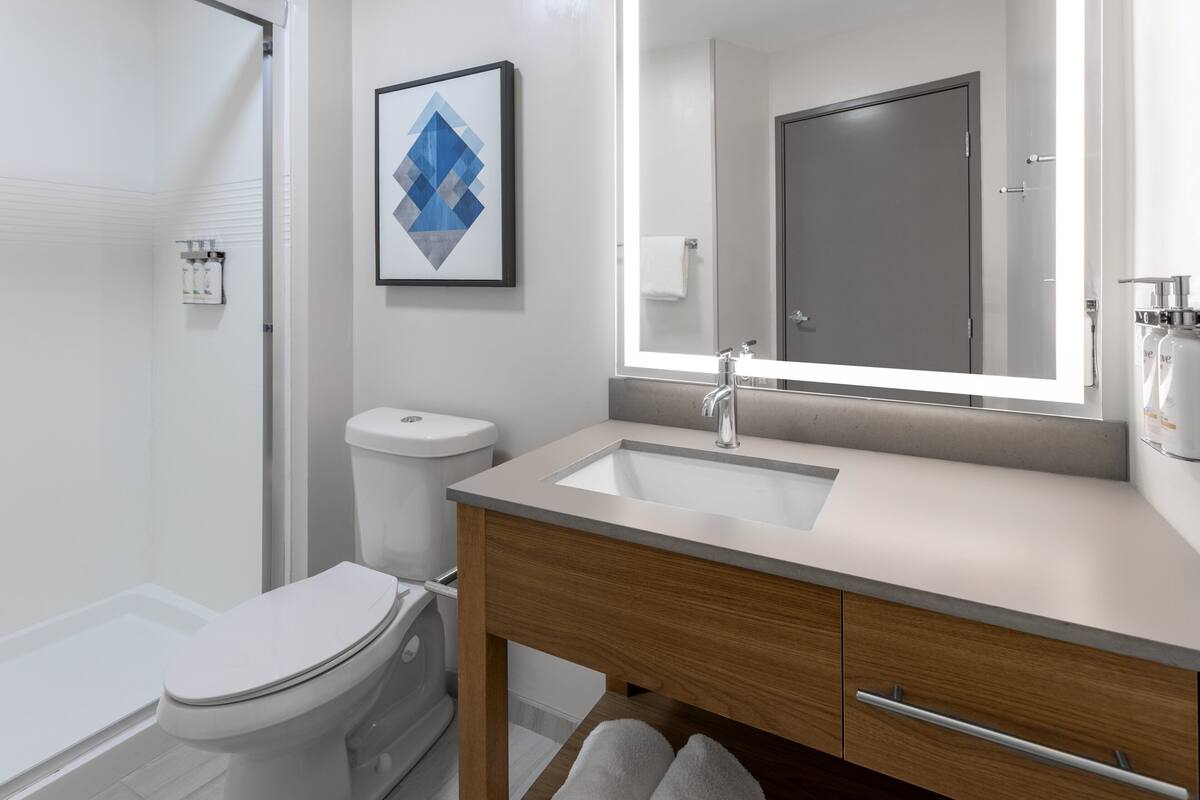 Une salle de bain moderne avec des toilettes, un lavabo et un miroir.