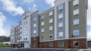 A multi-story hotel with a modern facade, a prominent entrance, and a parking lot.