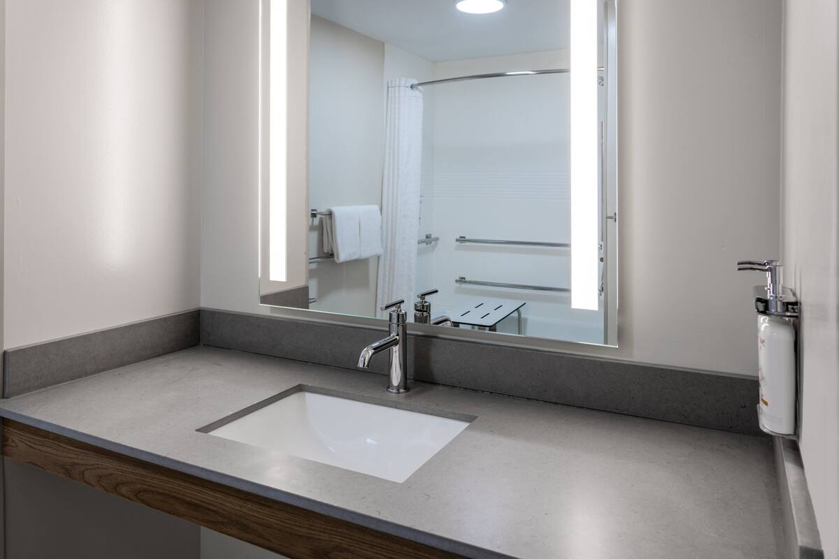 Une salle de bain avec un grand miroir, un lavabo et une douche.