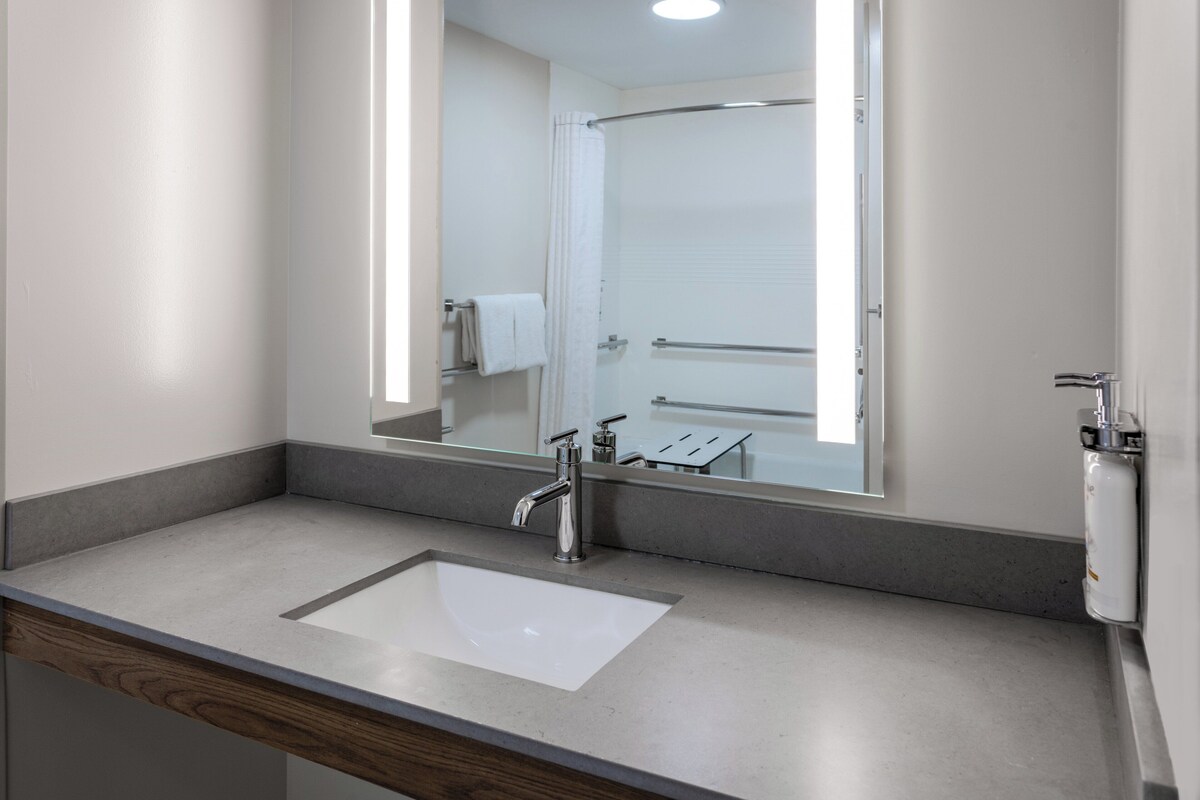 Une salle de bain avec un grand miroir, un lavabo et une douche.