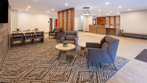 A modern hotel lobby with a reception desk, seating area, and a patterned carpet.