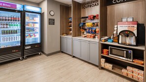 A coffee shop with a coffee machine, a microwave, and a refrigerated display case with beverages.