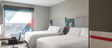 Une chambre d’hôtel avec deux lits, un bureau et une chaise.