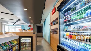 Un espace moderne dédié à la vente de produits alimentaires et de boissons, doté de vitrines réfrigérées et d’étagères remplies de collations et de boissons.