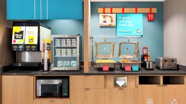 A breakfast bar with vending machines, a toaster, and labeled food containers.
