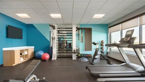 A gym with treadmills, exercise balls, and a wall-mounted TV.