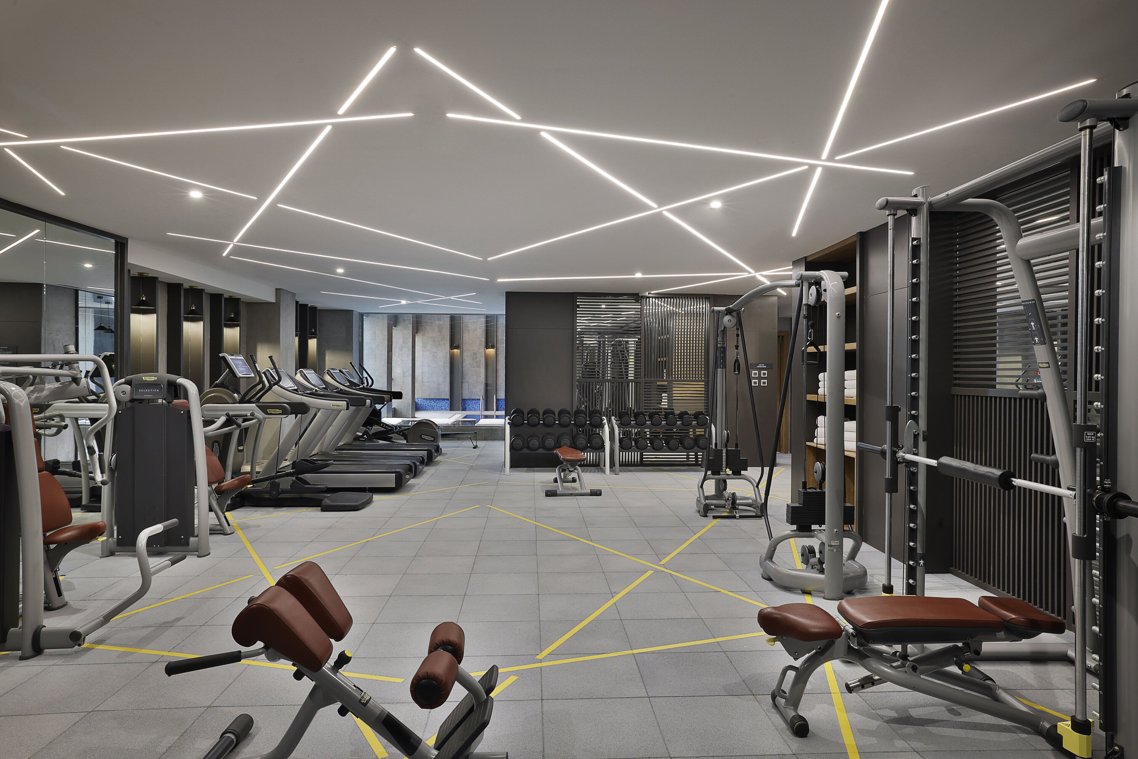 Una palestra moderna con tapis roulant, macchinari per pesi e uno specchio a parete.