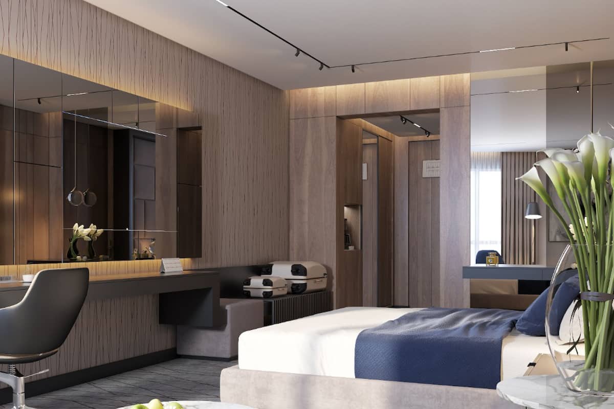 Ein modernes Hotelzimmer mit einer Wandpaneele aus Holz, einem großen Spiegel, einem Schreibtisch mit Computer und einem Bett mit blauer und weißer Bettdecke, sowie einer Vase mit Blumen.