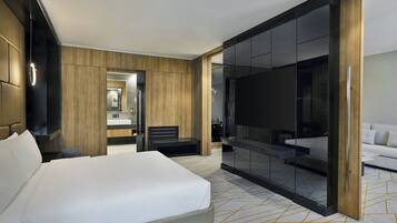 Ett modernt hotellrum med en stor säng, en sittgrupp, en glasvägg och en soffa.