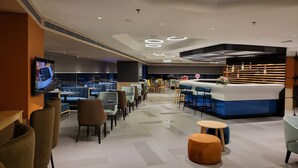 A modern hotel lobby with a reception desk, seating areas, and a large screen displaying content. - Holiday Inn Express & Suites Jaipur Gopalpura by IHG (Jaipur)