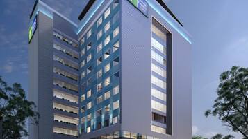 A modern hotel building with a prominent 'Holiday Inn Express' sign, multiple floors, and a parking area.