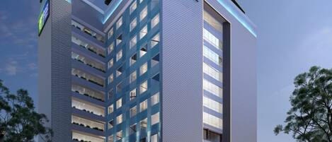 Un edificio moderno de hotel con un llamativo letrero de 'Holiday Inn Express', varios pisos y un área de estacionamiento.