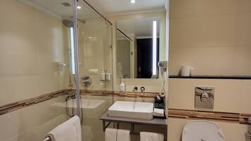 Une salle de bain moderne avec une douche à parois de verre, un meuble-lavabo à deux vasques, des toilettes et un miroir.