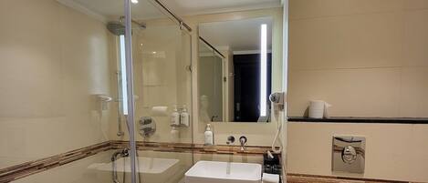 A modern bathroom with a glass shower enclosure, a double sink vanity, a toilet, and a mirror.