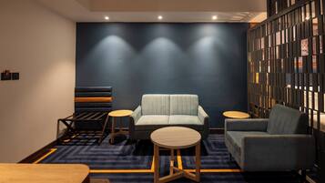 A modern lounge area with a sofa, two side tables, and a patterned carpet.