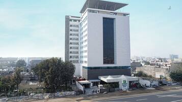 Un edificio de varios pisos con un elemento vertical destacado, techo plano y un local comercial en la planta baja.