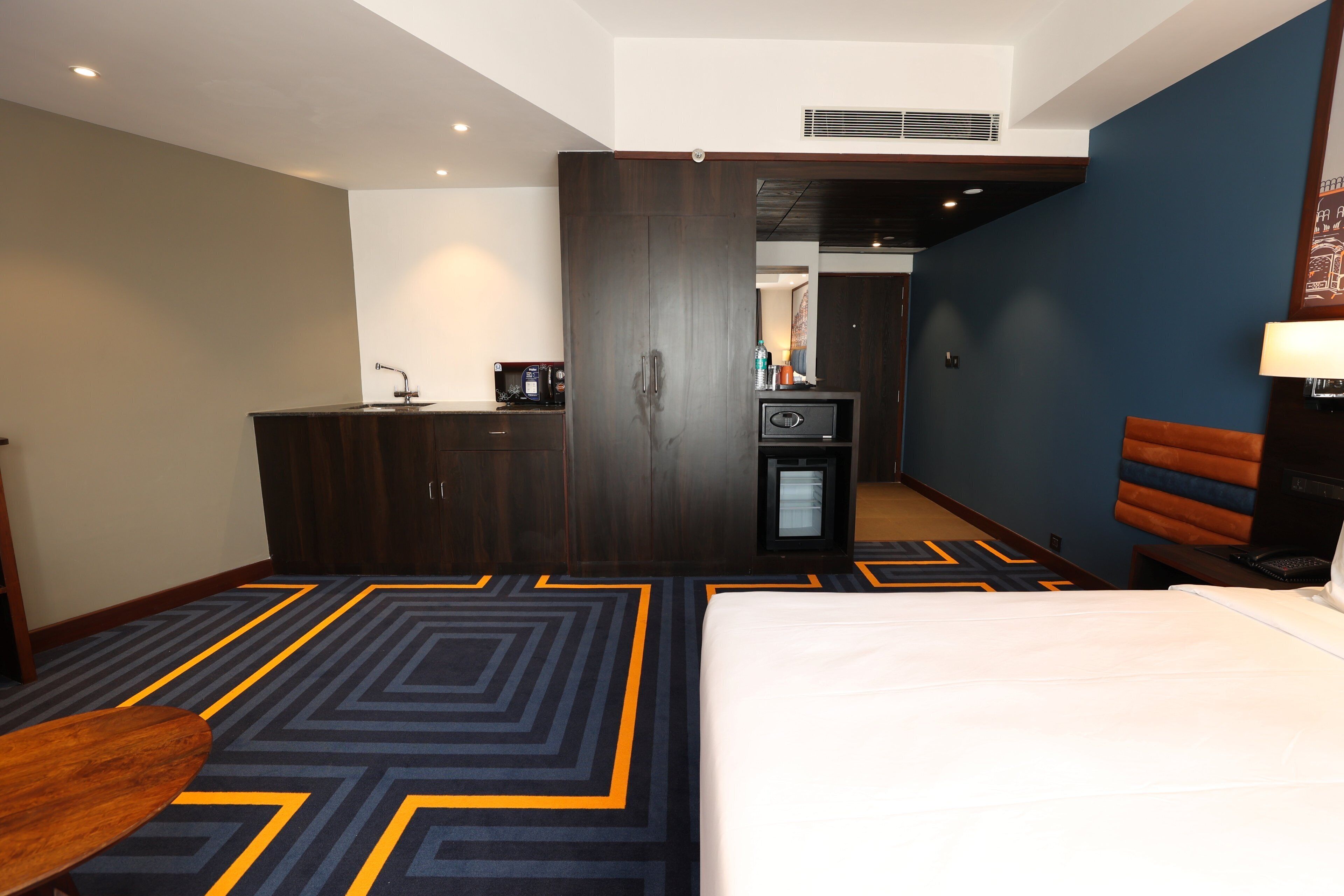 Habitación de hotel con cama, escritorio con ordenador, minibar y zona de estar.
