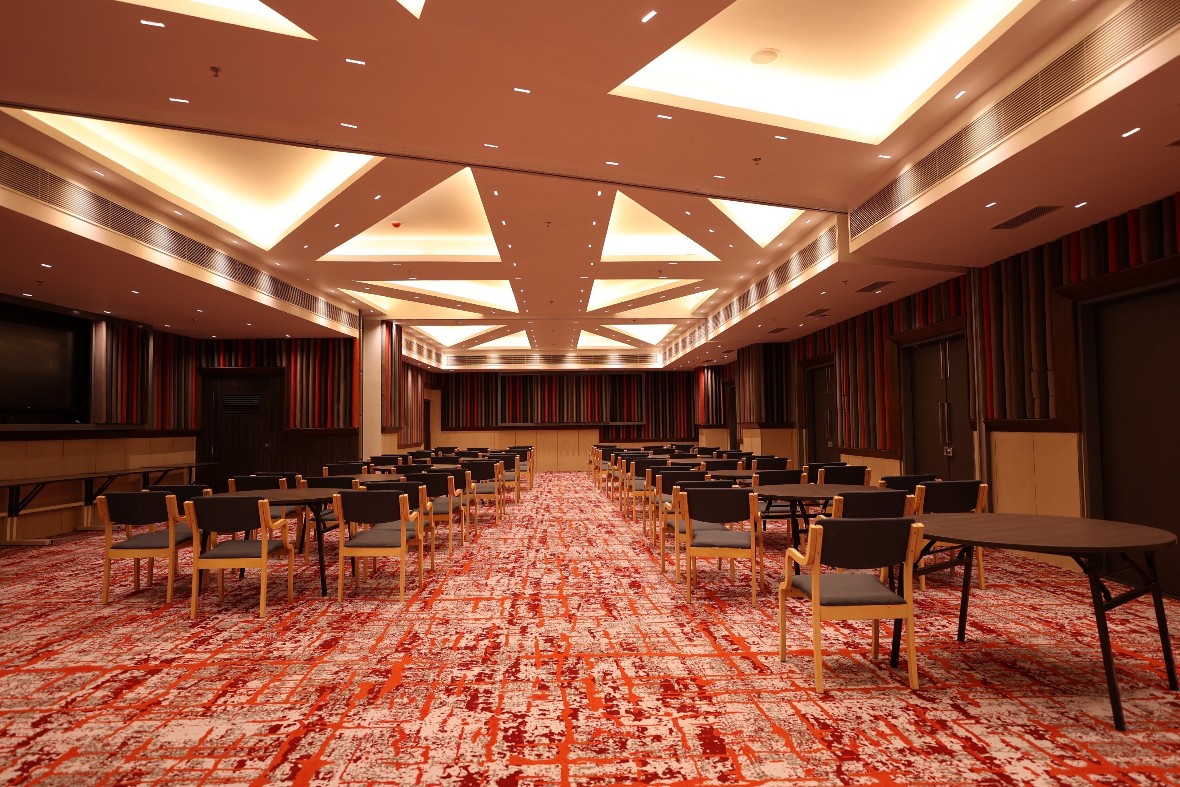 A conference room with a patterned carpet, multiple tables, and chairs arranged for meetings.