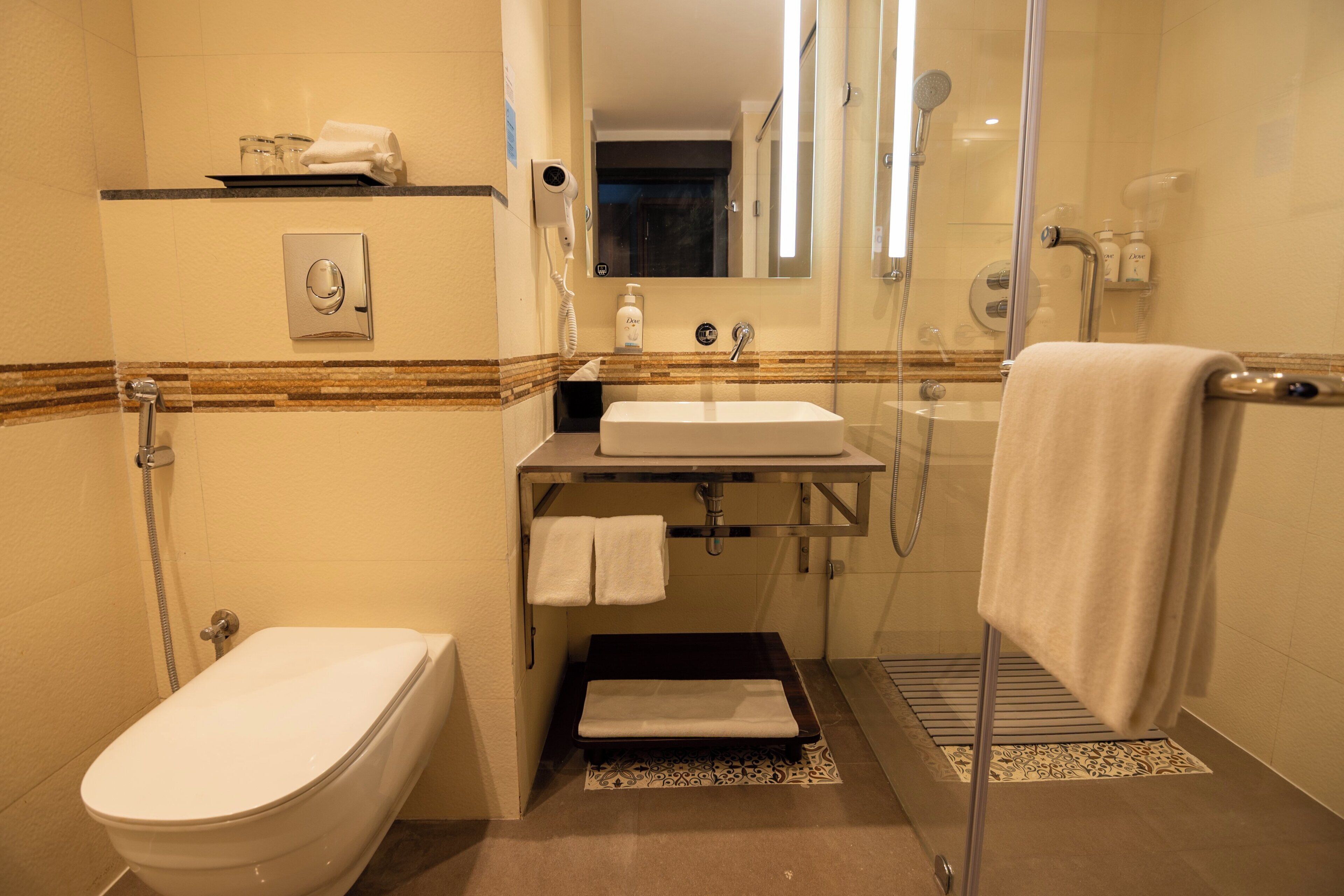 A modern bathroom with a toilet, sink, and shower.