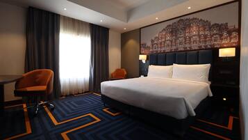 Una camera d'albergo con un letto, una scrivania, una sedia e un grande murale.