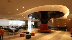 A spacious lobby with a unique architectural centerpiece, modern seating, and a well-lit environment. - Holiday Inn Express & Suites Jaipur Gopalpura by IHG (Jaipur)
