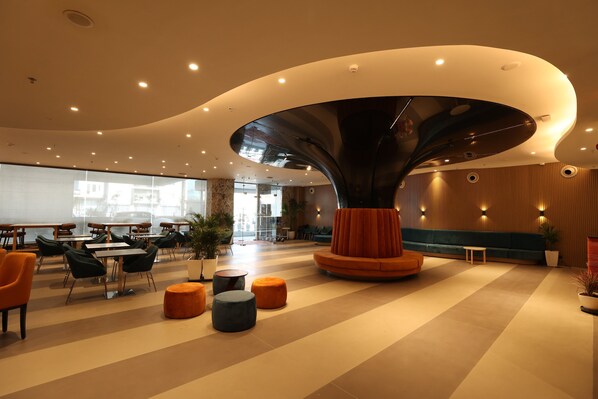 Un hall d’entrée spacieux, doté d’un élément architectural remarquable, de mobilier contemporain et d’un éclairage soigné.