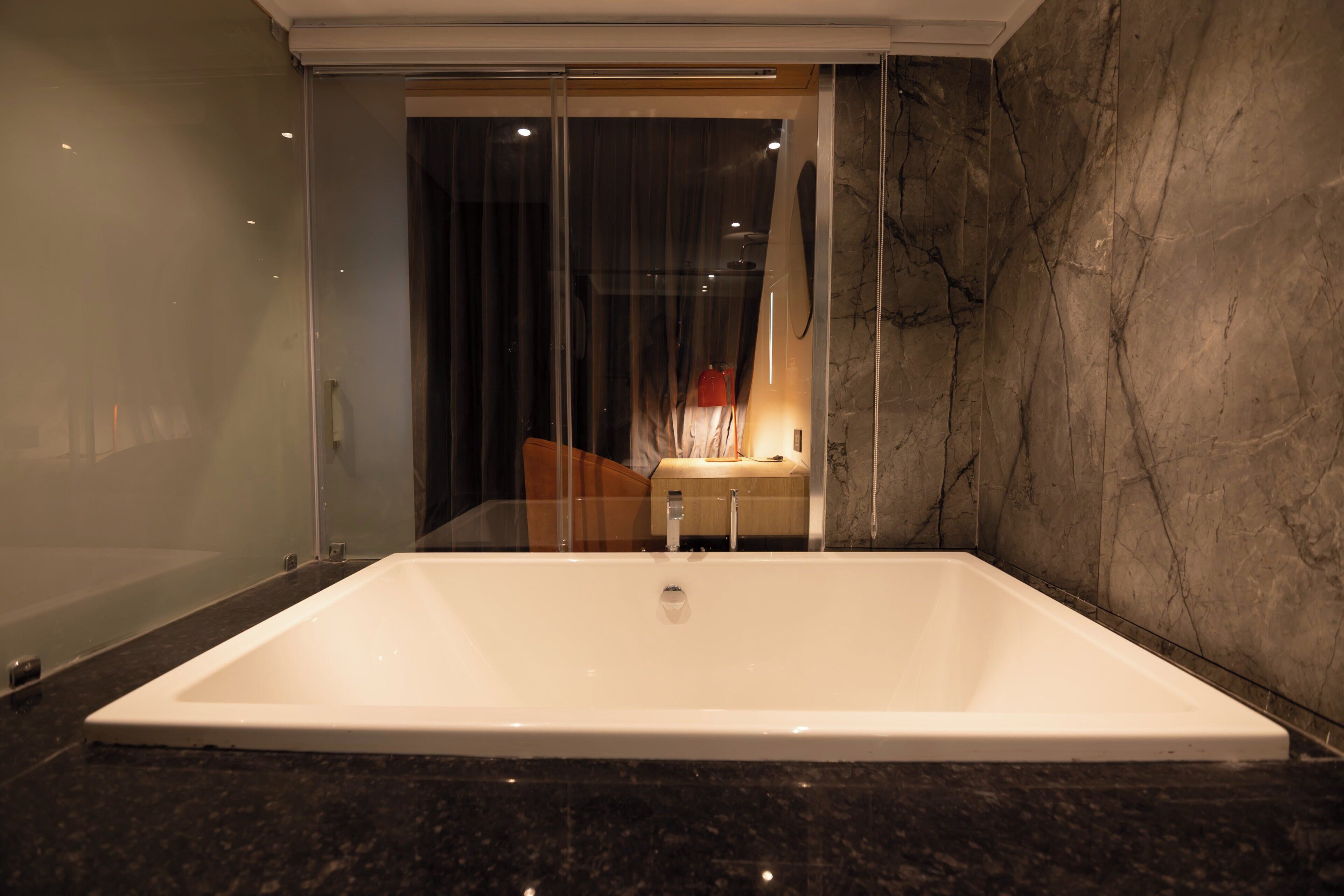 Ein modernes Badezimmer mit einer großen Badewanne, einer Duschkabine aus Glas und Marmorwänden.