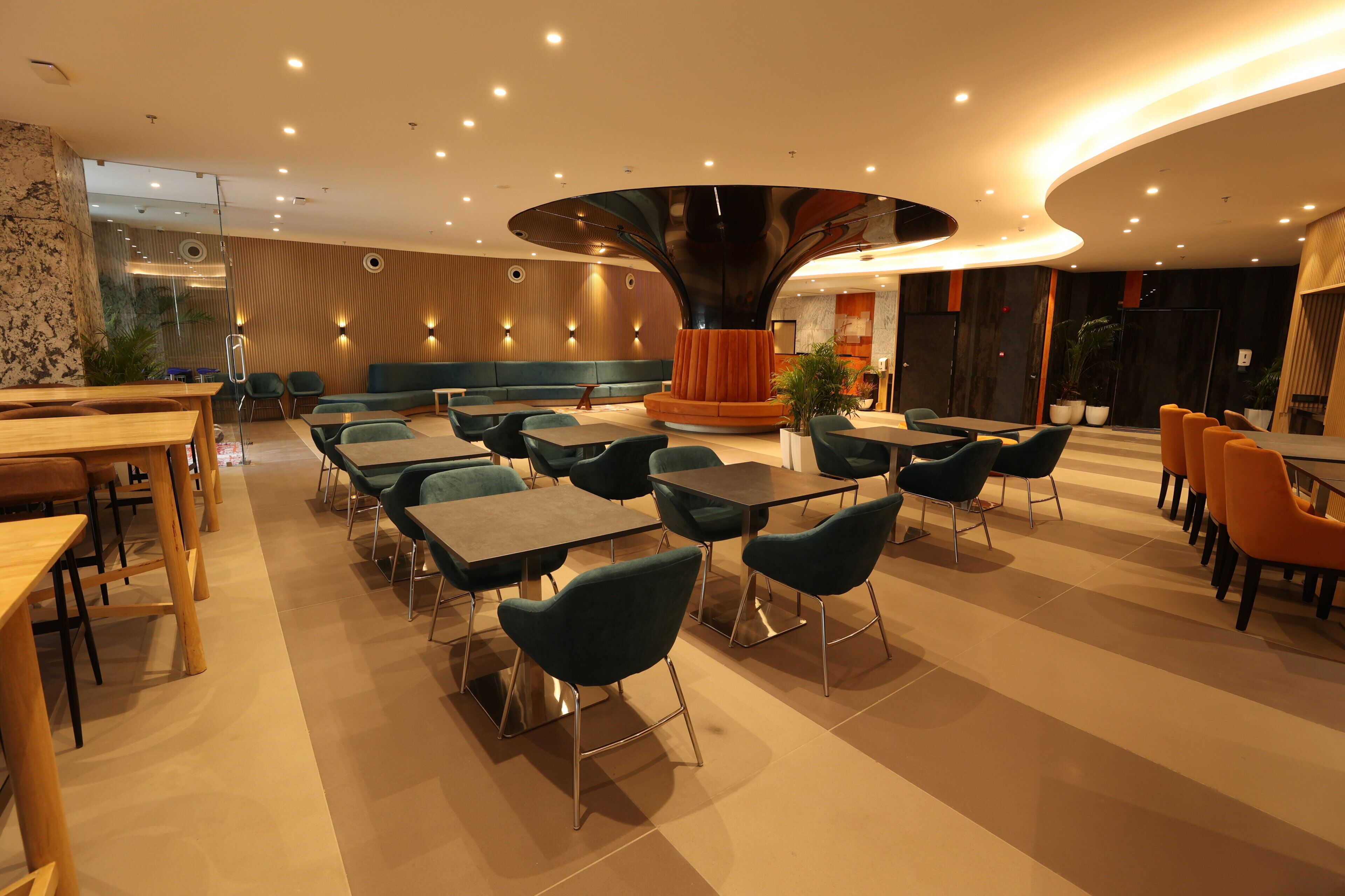 Een modern restaurantinterieur met verschillende zithoeken, waaronder tafels en zitbanken, en een decoratief middelpunt.