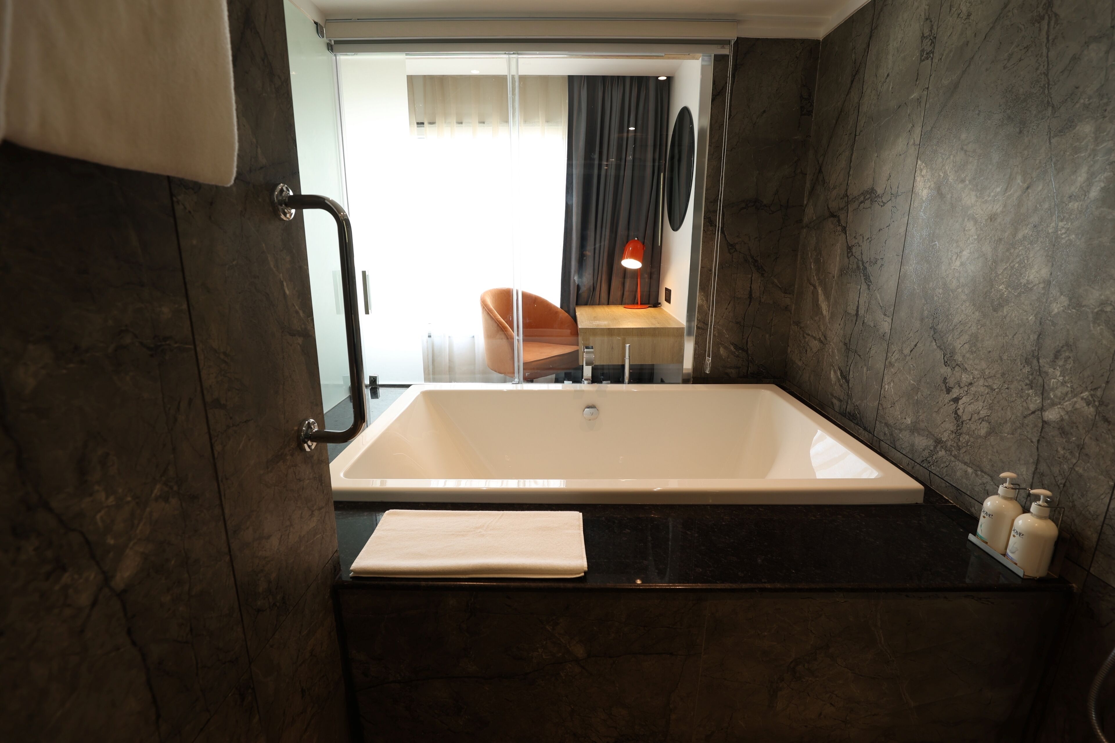 Ein modernes Badezimmer mit einer großen Badewanne, einer Duschkabine aus Glas und einer Sitzecke mit Tisch und Stuhl.